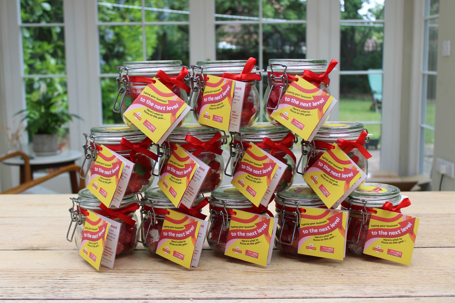 Jars with red ribbons and yellow labels on a wooden table